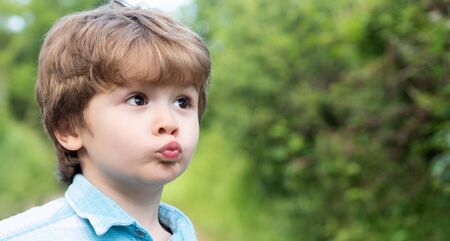 Cute kiss. Child with kiss icon gesture. The little boy made funny lips. Preschooler. Love and family. Surprised child on the background of nature.の写真素材