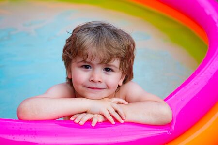 Summer relaxation in the pool. A child lies and relax in a home pool with a smile. Summer rest. Vacations. Cute baby swimming. Resort for the family.の写真素材