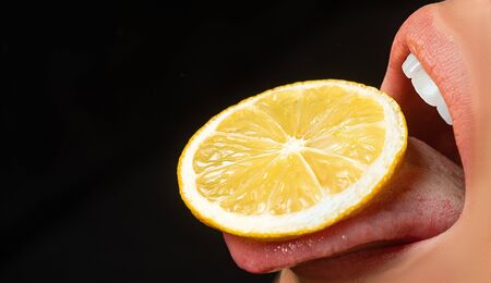 Lemon on the tongue. Cocktail concept. Girl with a lemon in the mouth. Sexy taste.の写真素材