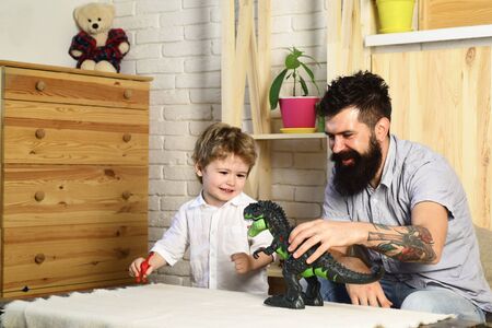 Dinosaur game. Father and son are played in the Jurassic period. Favorite toy. Boy with father in the childrens room.の写真素材