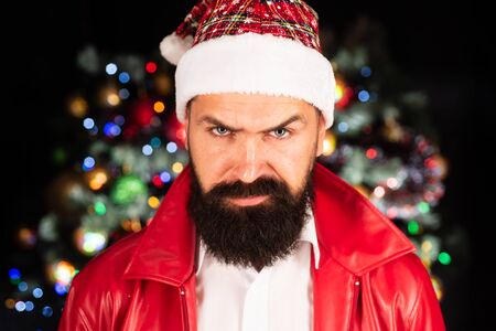 Bad Santa Claus in santa hat. Christmas emotional portrait. Portrait of a brutal mature Santa Claus. Angry man in santa hat. Emotional face.の写真素材