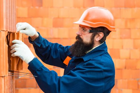 Construction Worker Contractor Man. Orange buid background. Bricklayer industrial worker installing...