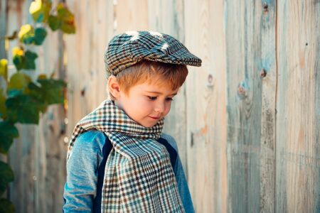Little boy on a wooden wall background. Humble shy child. Melancholy. Romance. Melancholic mood.の写真素材