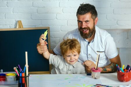Art for children. Bearded adult father teaches to draw little son in studio. Boy and man draw picture. Creative education and art, development in kindergarten. Childhood with parents talented teacher.の写真素材
