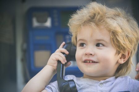 Communication, call on retro phone. Black handset in child little tender hand. Joyful boy speaks on...