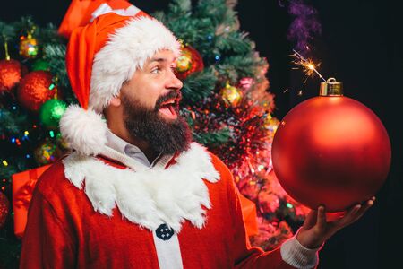 Christmas bomb. Christmas surprise. Bearded Santa is holding a toy for the Christmas tree in the form of a bomb.の写真素材