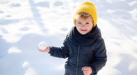 Snowballs. Child playing snowballs. Beautiful cheerful baby in the winter snow. Smile and happiness....