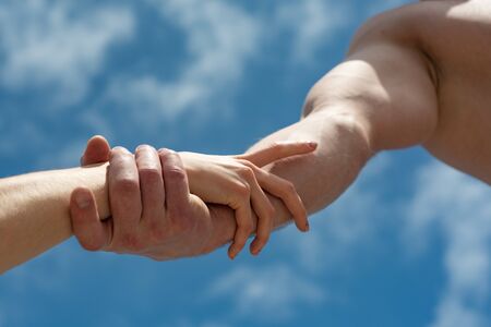 Friendship and help. Support. Two hands on sky background. Man and woman
