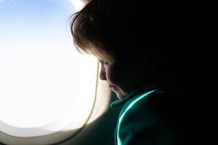 A child near the window porthole in an airplane. Travel, flight. Transport, travel memories....