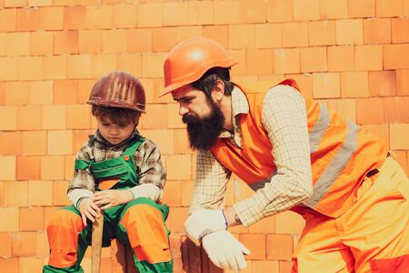 Construction concept. Brick. Teamwork. Son helps father build brick walls. Hard physical labor.の写真素材