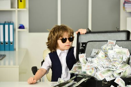 Boy in sunglasses with a suitcase of money.の写真素材