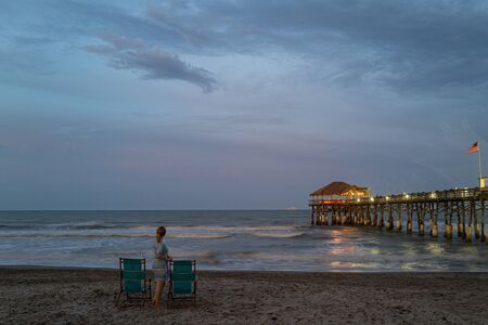 Single woman. A woman is looking at the ocean. A beautiful romantic evening in Florida. Romantic pier in South USA. Loneliness. Single girl.の写真素材