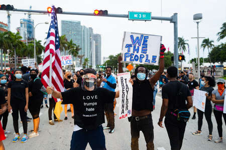 Miami, FL, USA - JUNE 7, 2020: Love Trumps hate t-shirts. Black and white male masked by coronavirus pandemic. Posters at a demonstratioのeditorial素材