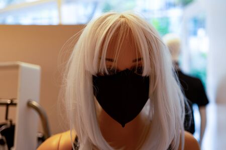 Woman in a black mask. Mannequin in a shop window. Pandemic Blondeの写真素材