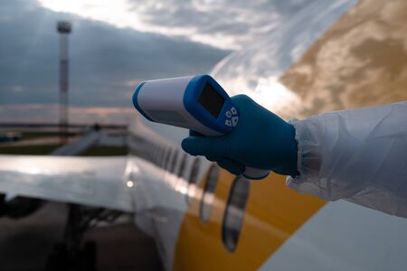 Covid 19, coronaviruse protection. Measure body temperature at the border and aeroport. A steward in...