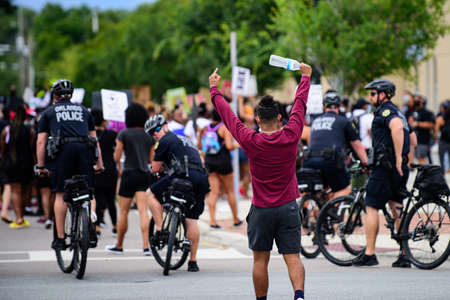 Orlando, FL, USA - JUNE 19, 2020: Police and demonstrators. Protest against police actions. Young man showed finger to a policeman.のeditorial素材