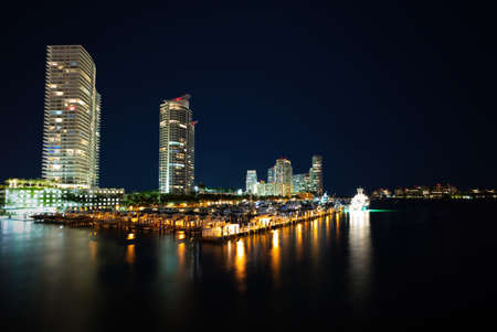 Miami city skyline panorama at dusk with urban skyscrapers and bridge over sea with reflection. Night in Miami.の写真素材