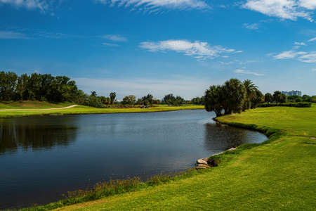 Beautiful Fairway At Golf Course. Artificial lake in golf course with beautiful green field.の写真素材
