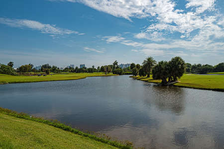 Tropical golf course with green field with trees, grass and lake.の写真素材