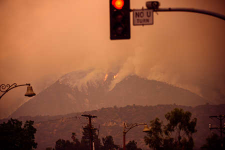 Huge fires in the mountains of the USA and blurred red traffic light.