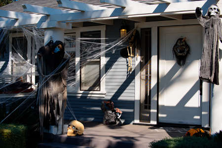 Death wearing a mask for coronavirus. Cobweb as decoration. Halloween scenery. Terrible holiday at home. Halloween in the USA. Traditions and house decor.の写真素材