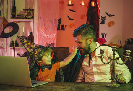 Funny family. Father and son are happy with online shopping. Happy family near laptop. Autumn holidays and Halloween.の写真素材