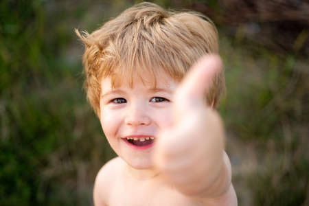 Happy child showing thumbs up. Handsome cheerful 4 years old boy giving thumbs up into camera as symbol of success. Closeup of blonde cute happy kid with great smile.の写真素材