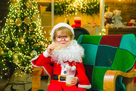 Little boy Santa Claus eating cookies and drinking milk on Christmas Eve.の写真素材
