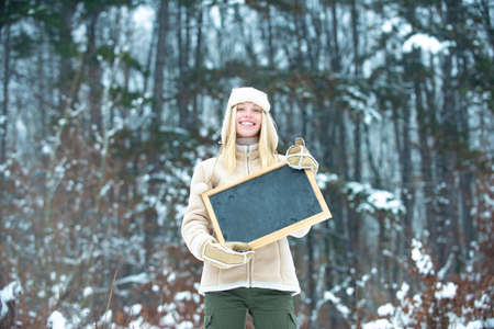 Happy girl with advertising on background of winter forest.の写真素材