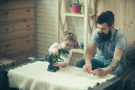 Dinosaur game. Father and son playing at home. Family having fun. Concept of friendly family. Father and boy are smiling while spending time together at home. Fathers day.の写真素材
