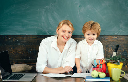 Teacher helping kids with computers in elementary school on the USA. Digital education online.の写真素材