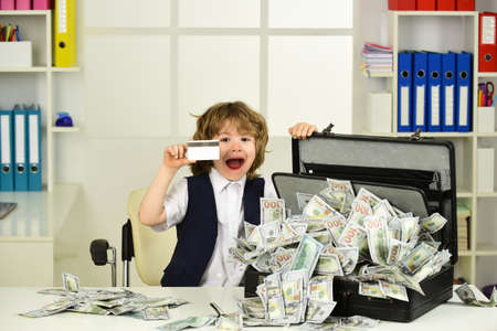 Lottery, win. The child shows a bank card and a suitcase of dollars in cash.の写真素材