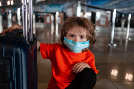 A child with a mask on his face and a suitcase for travel.の写真素材