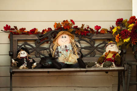 Autumn decorations on a bench near the house. Cozy yard and yellow leaves of November and October. Dolls puppetの写真素材