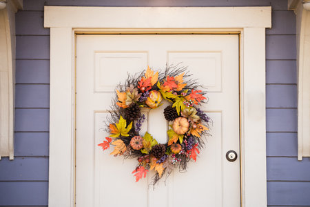Autumn wreath on the door. Yellow and red leaves and pumpkins. Scenery for a cozy house in the fall before Halloween.の写真素材
