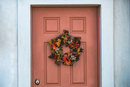 Autumn wreath on the front door with flowers. Scenery for Halloween in October. Decoration in the yard.の写真素材
