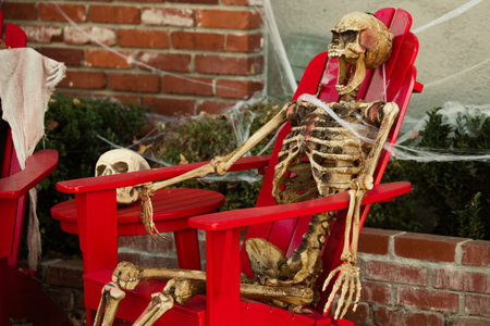 The skeleton relaxes in an outdoor chair. Scenery for Halloween in October. Decoration in the yard.の写真素材