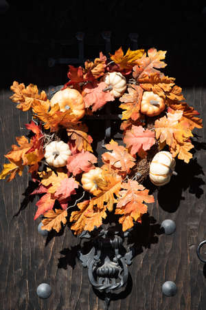 Autumn wreath on the front door withleaves, flowers an pumpkins. Scenery for Halloween in October. Decoration in the yard.の写真素材