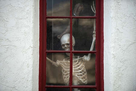 Skeleton in the house outside the window. Scenery for Halloween in October. Decoration in the yard.の写真素材