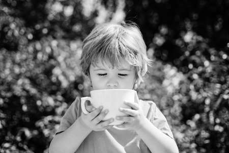 Happy baby with a cup of milk or tea. Baby drink.の写真素材