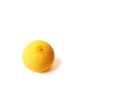 Round yellow melon on the white surface on the left. Texture and shadow. Lots of empty space for text. Minimalistic image.の写真素材