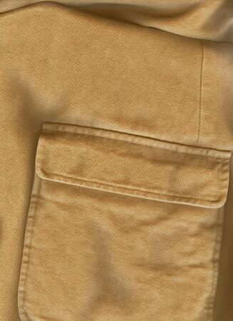Closeup pocket. Raw sienna or ocher color cotton shirt. English style. Solid fabric texture. Casual...