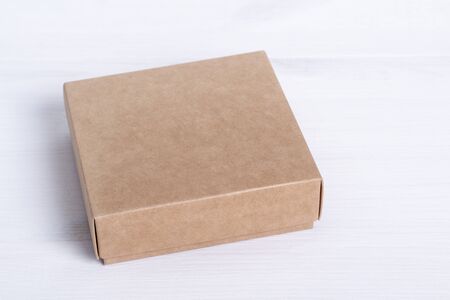 Blank cardboard box package isolated on white wood background. Craft paper box side view. Small...