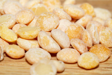 Raw split peas of yellow variety on the wooden surface and scattered beside, close-up in selective focus. Vegan food, stock photoの写真素材