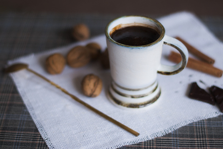 coffee cup and beans, cinnamon sticks, nuts and chocolate on wooden table on brown backgroundの写真素材