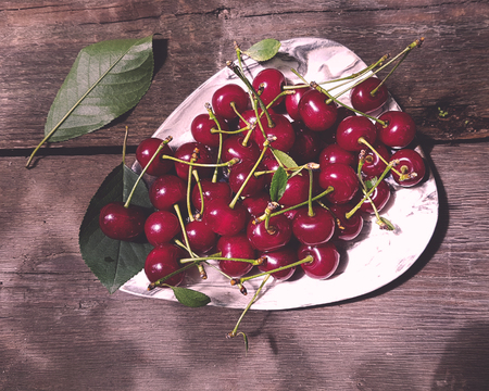 fresh red cherry fruit in plate on wood table backgroundの写真素材