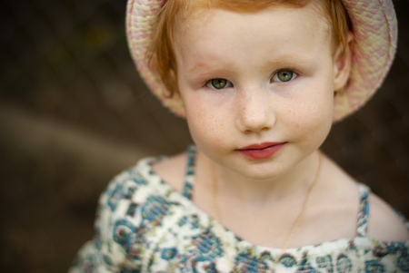 european girl with red hair and green eyes in a summer hat
