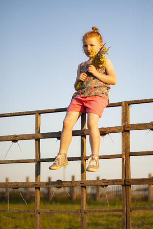 a child, a girl climbs a wooden fence in the village.の写真素材