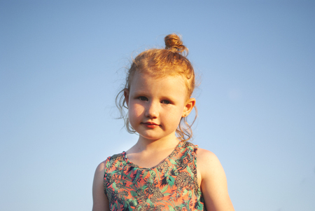 Happy young girl with a flower in his hand against the blue skyの写真素材