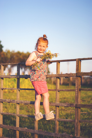Happy young girl with a flower in his hand against the blue skyの写真素材